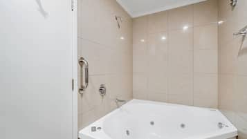A modern bathroom with a large bathtub, a showerhead, and a toilet.
