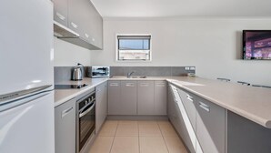 A modern kitchen with grey cabinets, a built-in oven, a dishwasher, and a window above the sink.