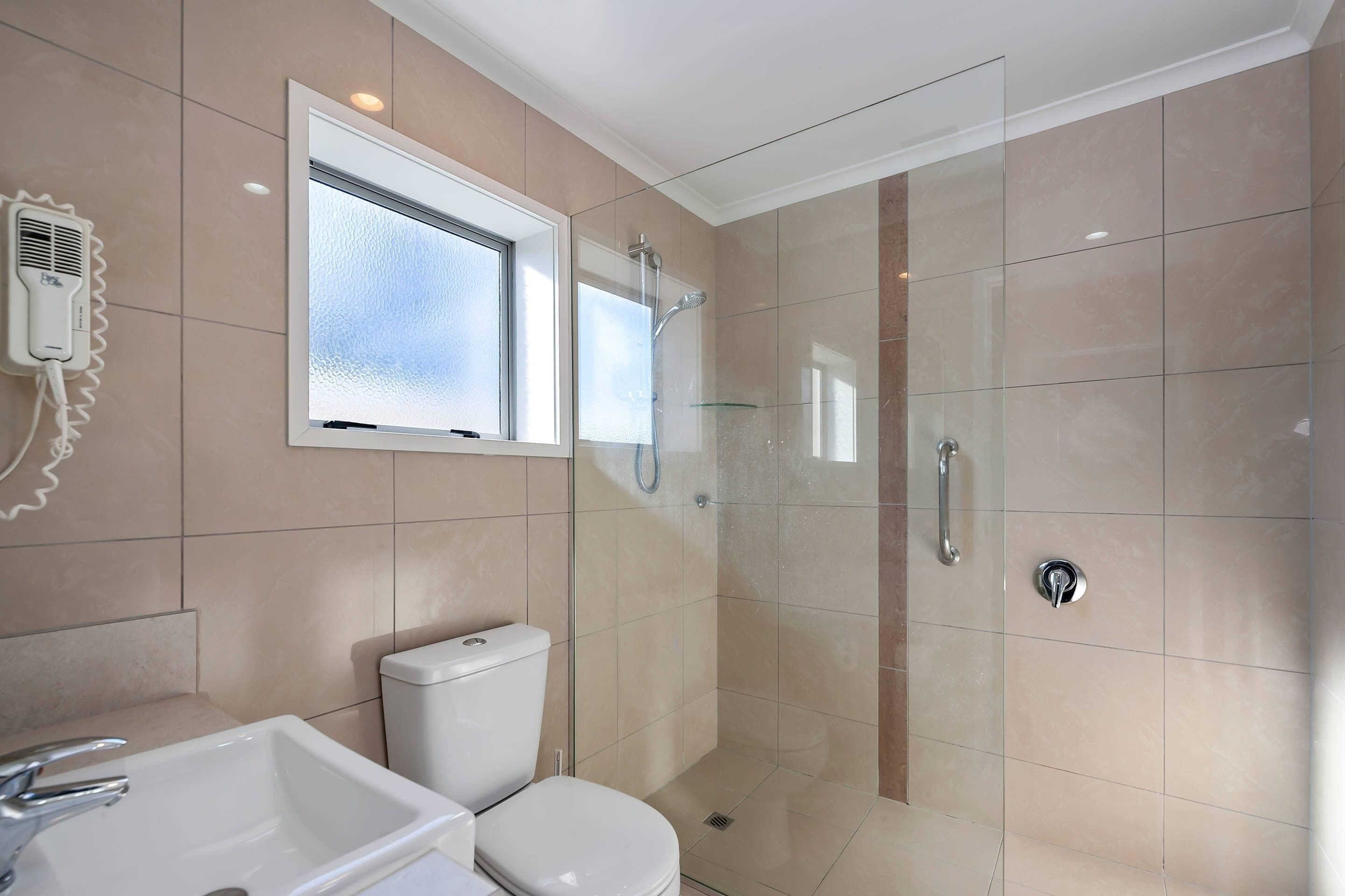 A modern bathroom with a toilet, sink, and glass-enclosed shower.