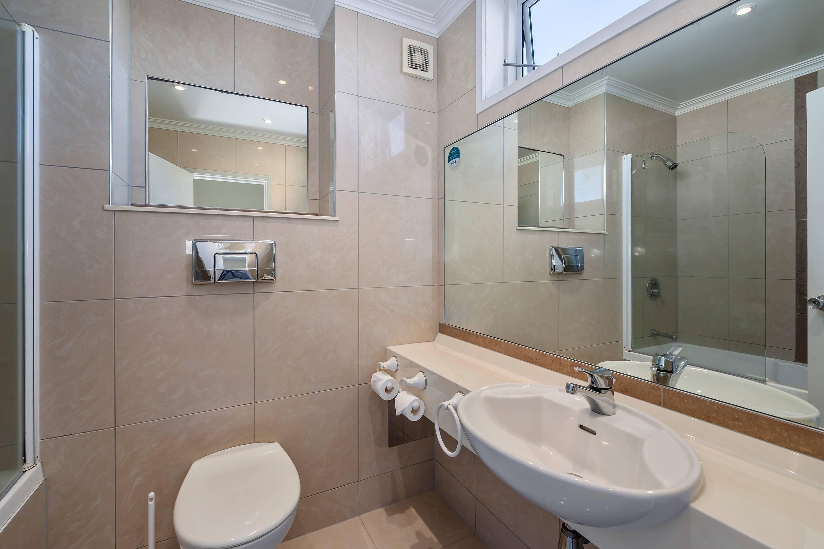 Ein modernes Badezimmer mit Toilette, Waschbecken und Duschbereich.