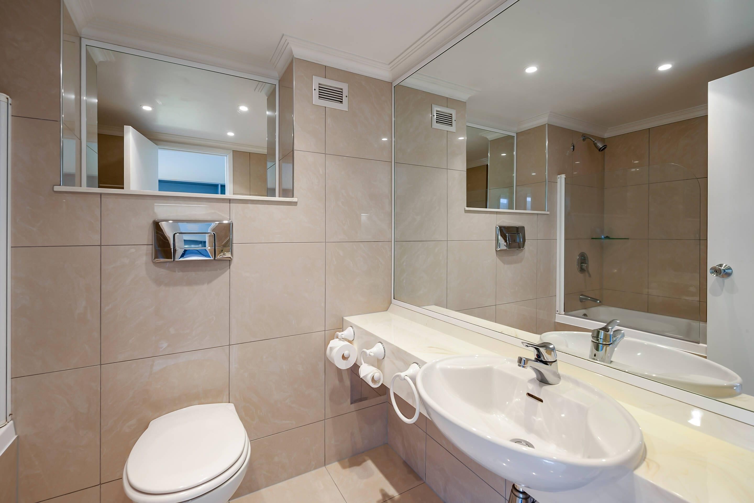 A modern bathroom with a toilet, sink, and shower.