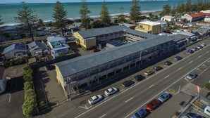 An aerial view of a coastal town with a prominent building featuring a large parking lot and a view of the ocean.