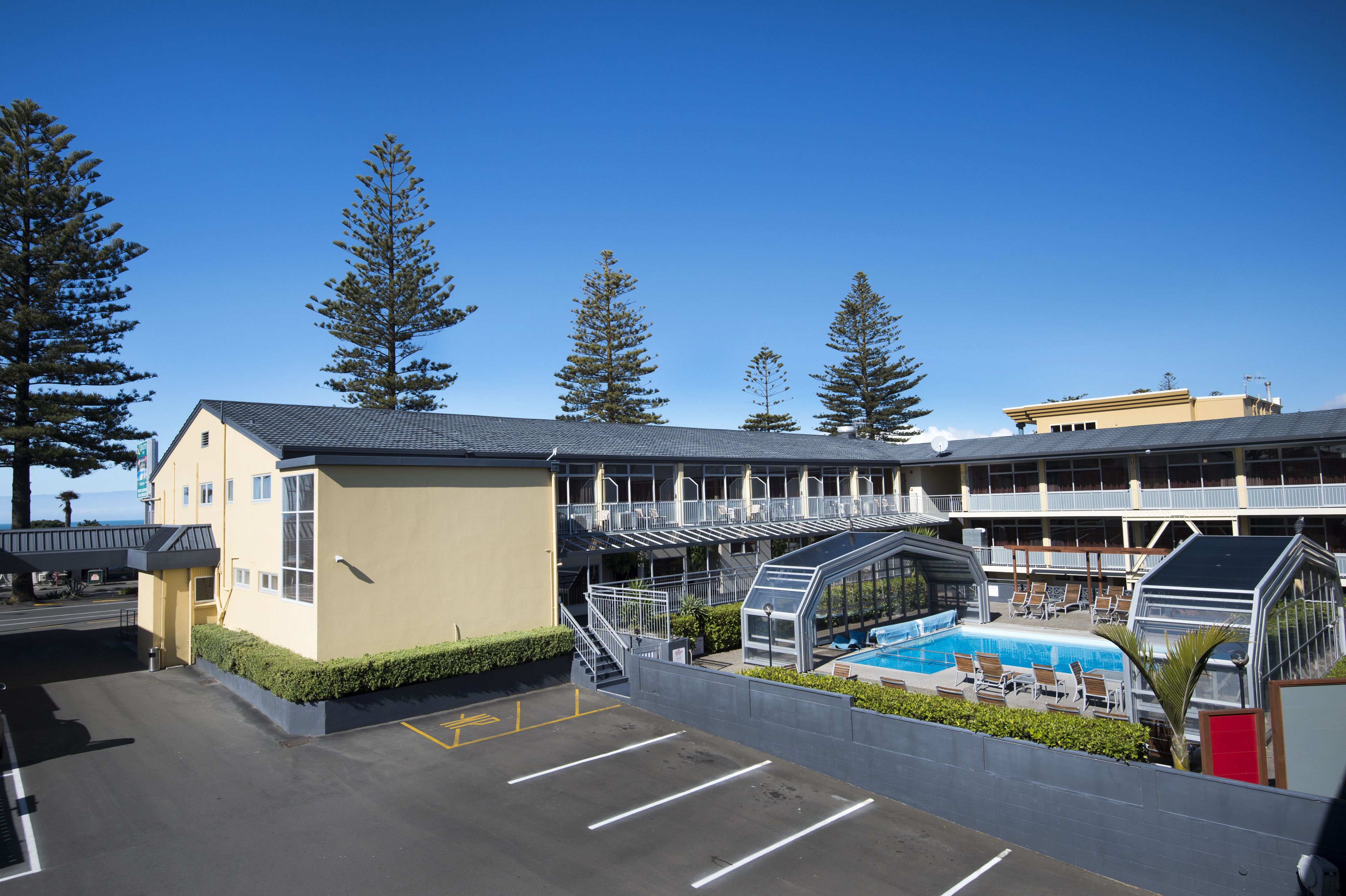 A hotel with a swimming pool, outdoor seating, and a covered area.