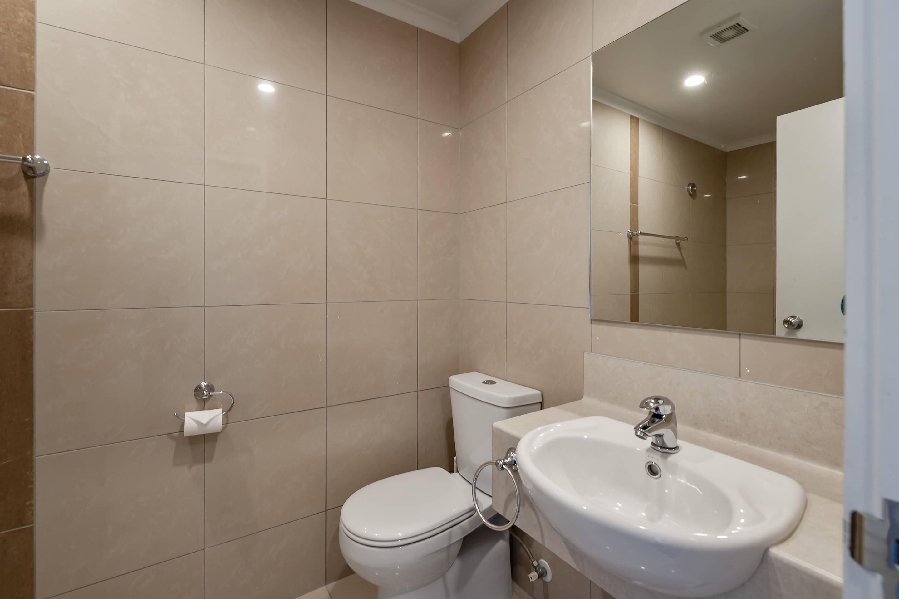 A bathroom with a toilet, sink, and mirror.