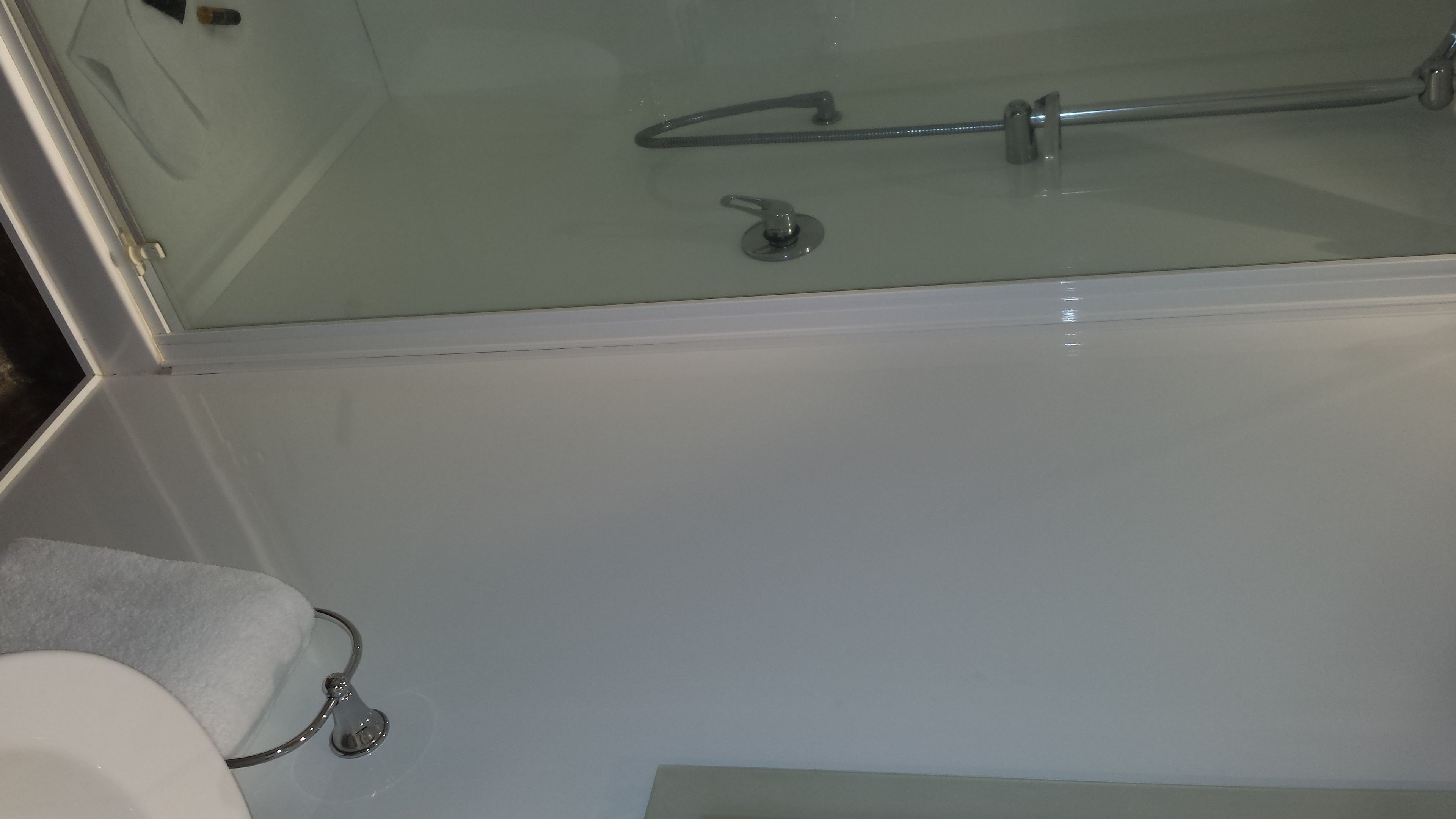 A bathroom with a glass shower enclosure, a white sink, and a towel rack.