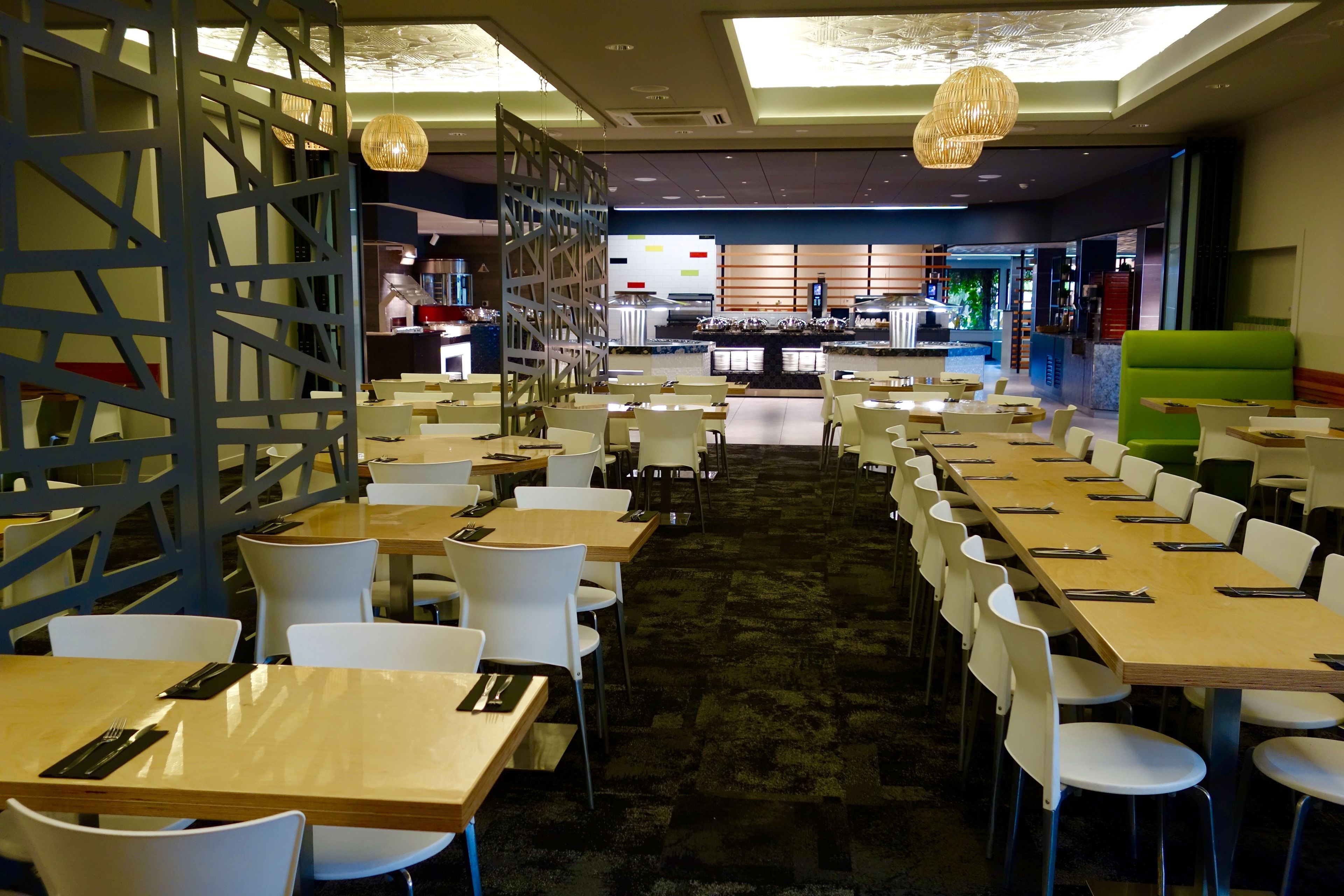 Un comedor amplio con varias mesas y sillas, una barra central y un diseño de interiores moderno.