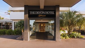 La entrada del Hotel Devon, con un diseño moderno, presenta una fachada de vidrio y un cartel sobre la entrada.