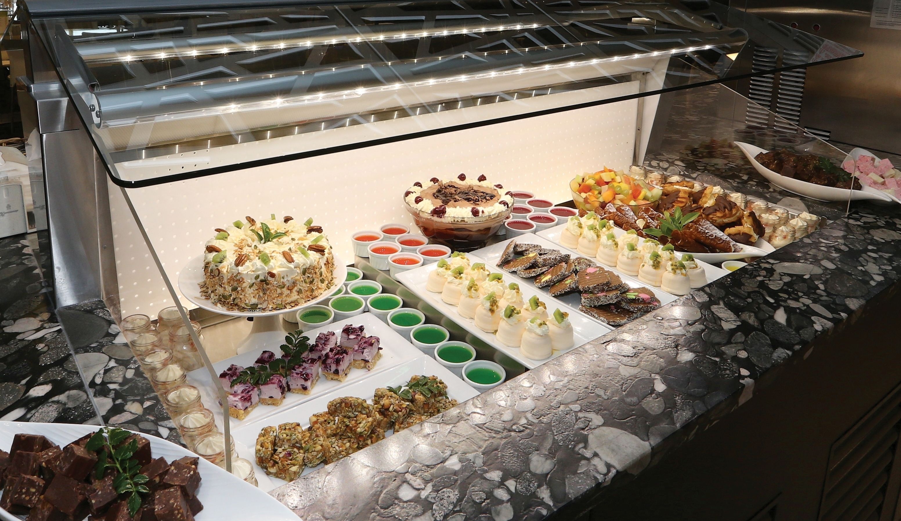 Ein Buffet mit verschiedenen Speisen, darunter Kuchen, Desserts und eine Auswahl an Vorspeisen.