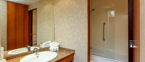 A hotel bathroom with two sinks, a shower, and a large mirror.