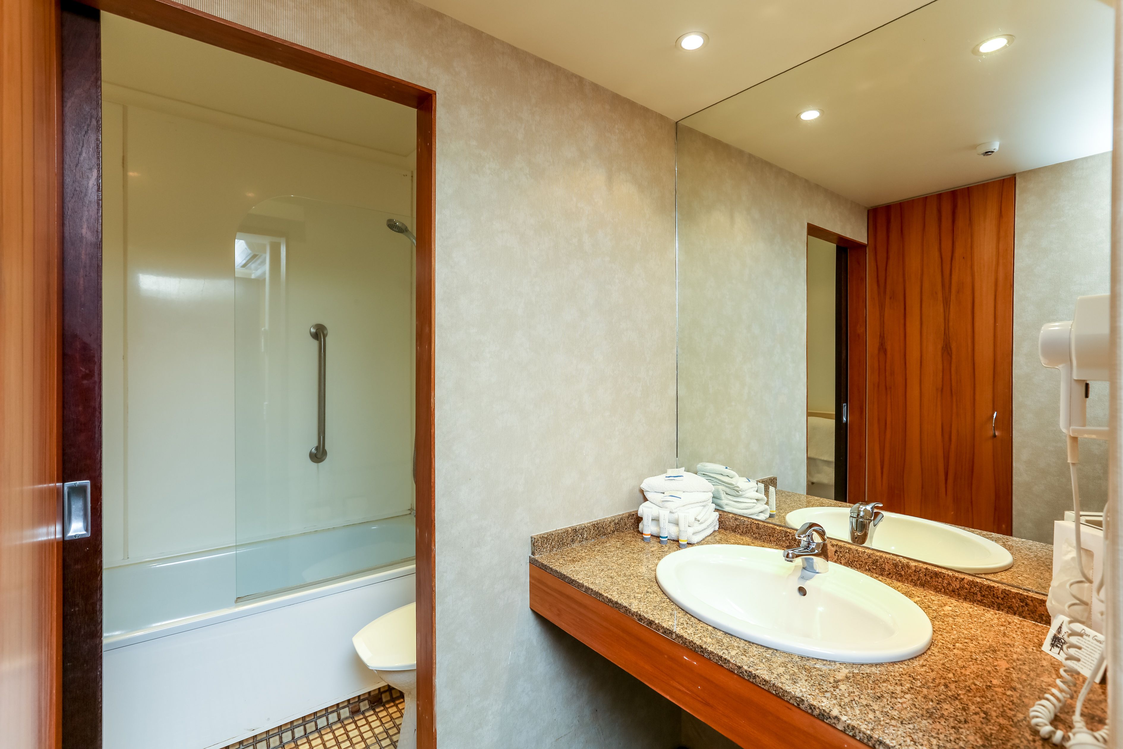A modern bathroom with two sinks, a glass shower enclosure, and a wooden vanity.