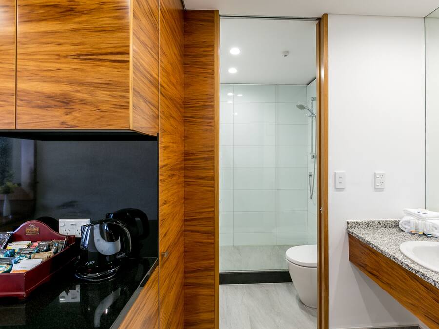 A modern bathroom with a wooden vanity, a sink, and a shower area.
