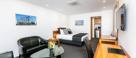 Una habitación de hotel moderna con cama, sofá, mesa de centro y escritorio.