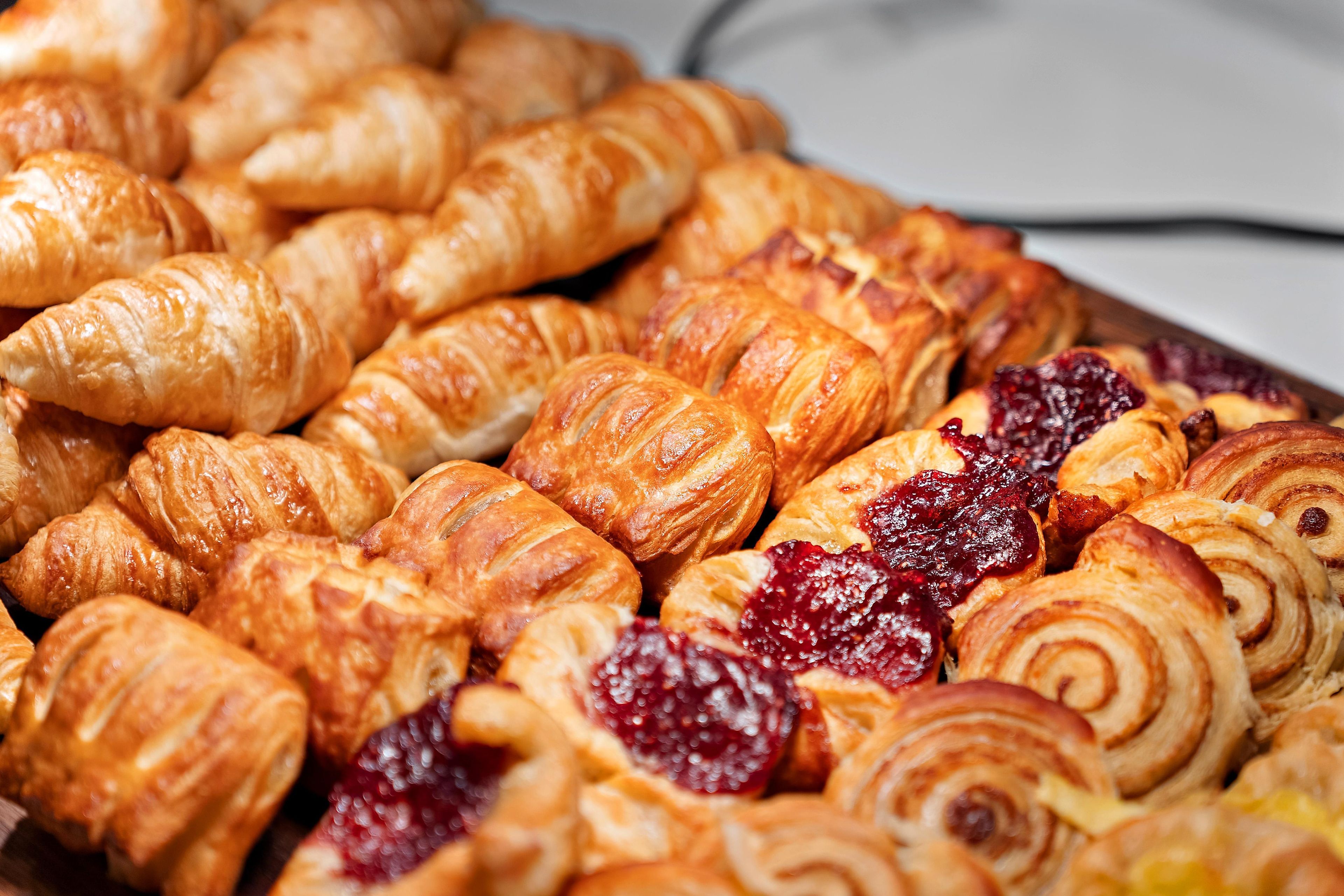 A variety of pastries, including croissants and pastries with fruit preserves.