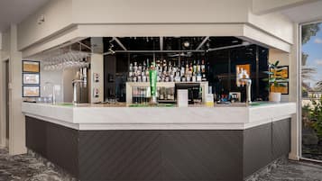 A bar area with a counter, various bottles, glasses, and a cash register.