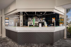 A bar area with a counter, various bottles, glasses, and a cash register.