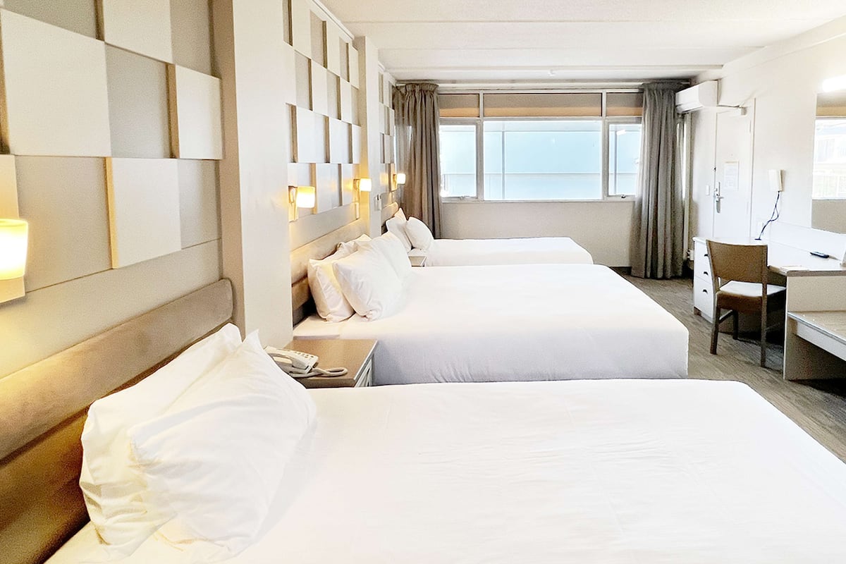 A hotel room with two beds, a desk, and a chair.