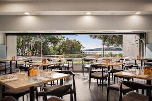 Un restaurante con mesas dispuestas para comer, vista a un lago y cielo despejado.