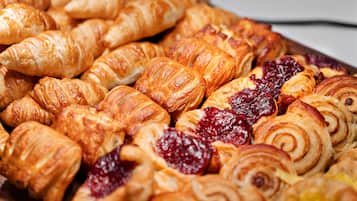 A variety of pastries, including croissants and pastries with fruit preserves.