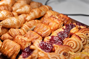Diverse gebakjes, waaronder croissants en gebak met fruitconfituur.