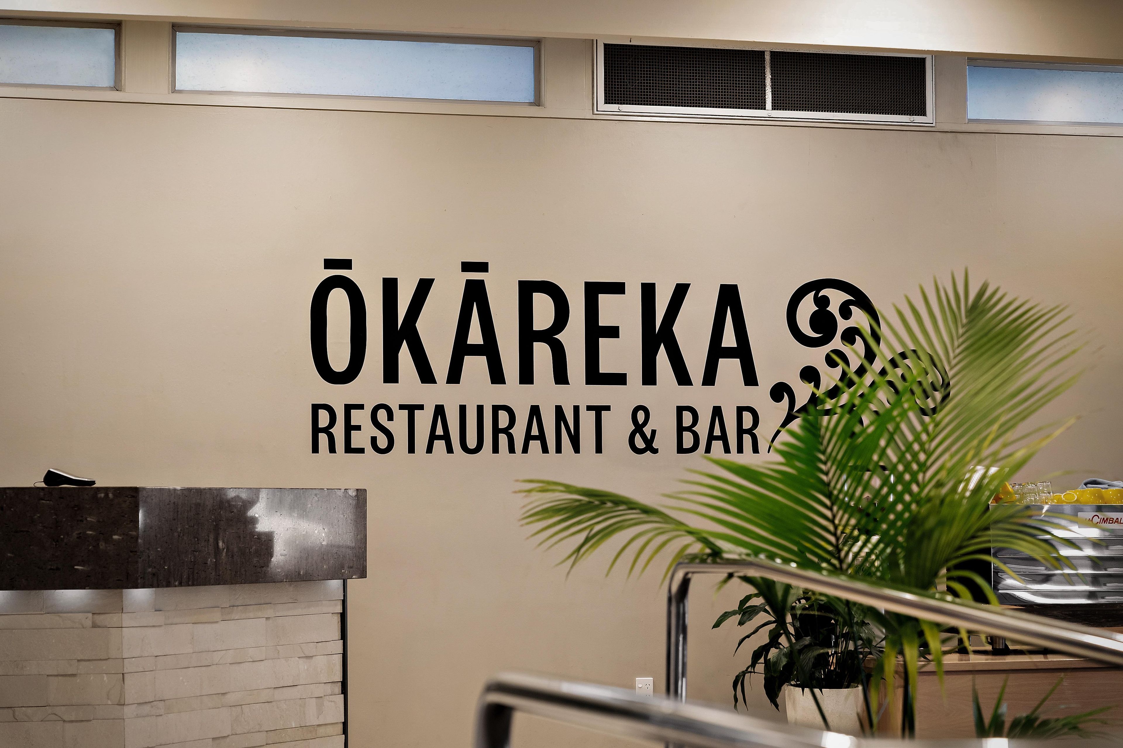 A wall with the sign 'ÖKAREKA RESTAURANT & BAR' indicating the establishment's name.