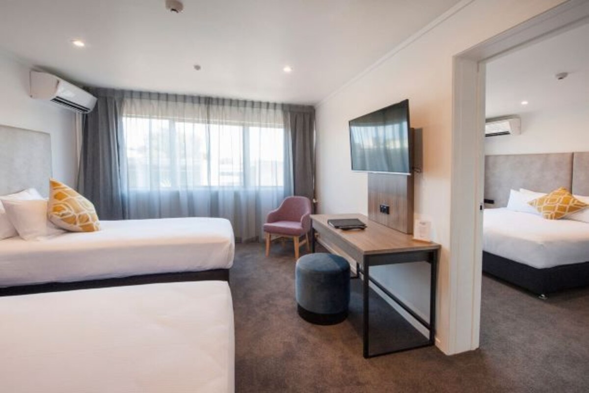 Una habitación de hotel con dos camas, un escritorio, una silla y una televisión.