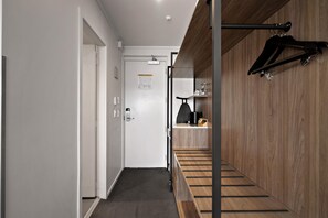Un intérieur moderne avec un escalier en bois, un porte-manteau et une porte sur laquelle est affiché un plan d’évacuation en cas d’urgence.