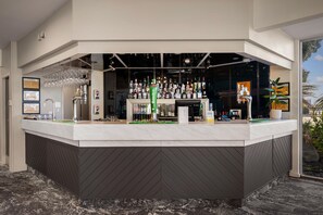 Zona de bar con mostrador, varias botellas, vasos y una caja registradora.