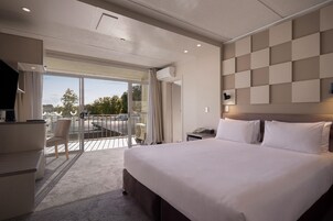 A hotel room with a large bed, a desk, a chair, a balcony with a view, and a modern wall design.