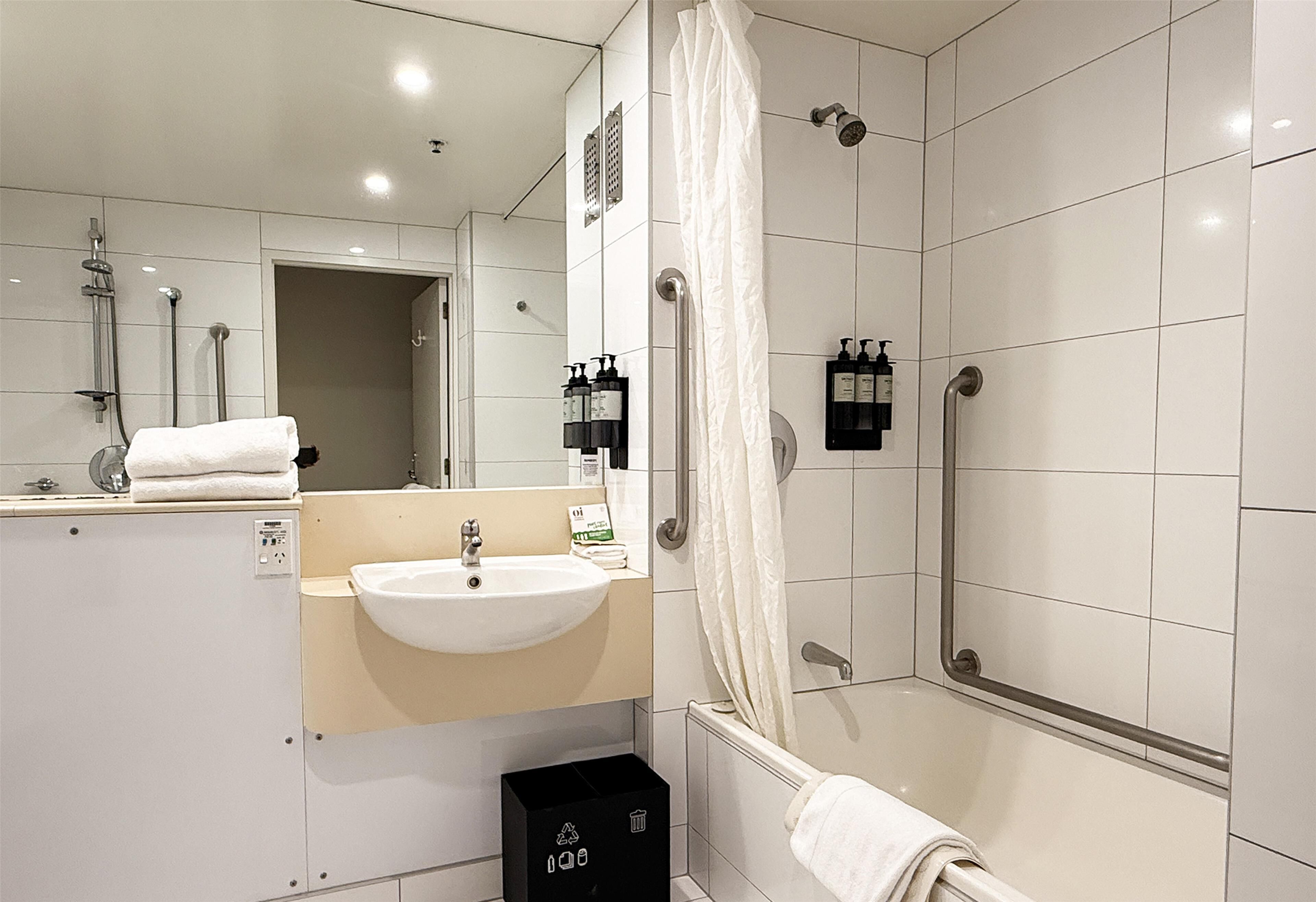Un baño moderno con lavamanos blanco, espejo, ducha e inodoro.