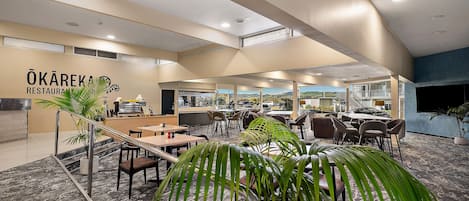 A restaurant interior with a bar area, seating, and a view of the outdoors.