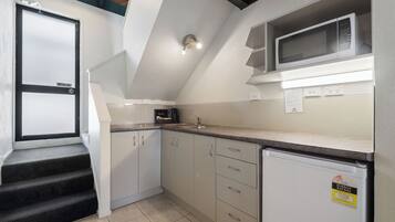 A kitchen with a microwave, refrigerator, and a sink. There are cabinets and a countertop.