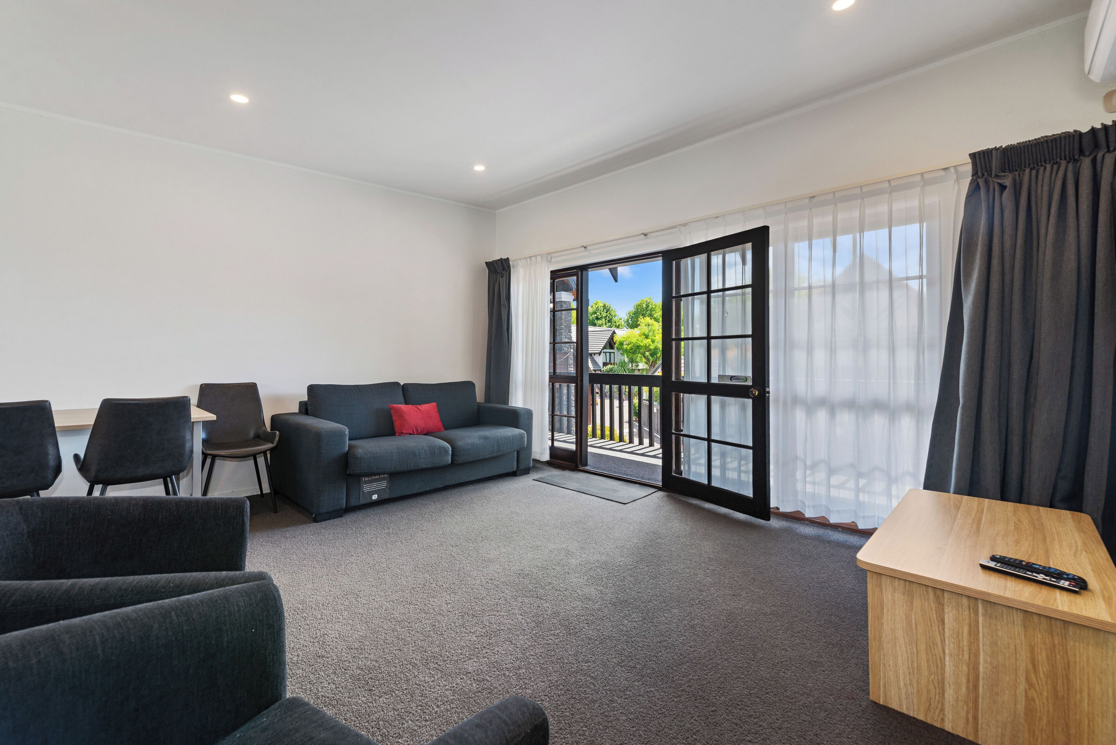 A modern room with a grey sofa, a small table, and a balcony with a glass door.