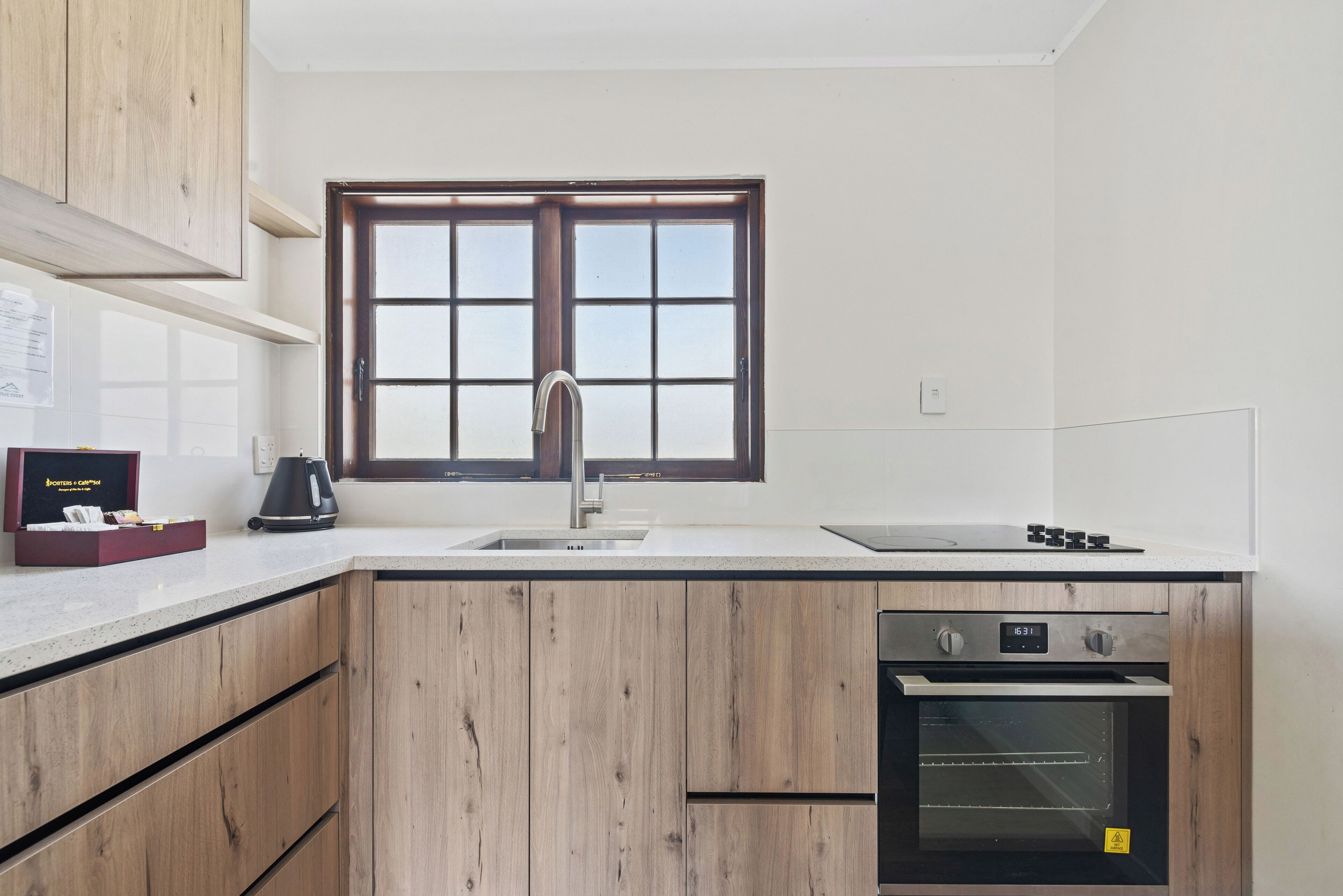 A kitchen with wooden cabinets, a sink, a stove, and an oven.