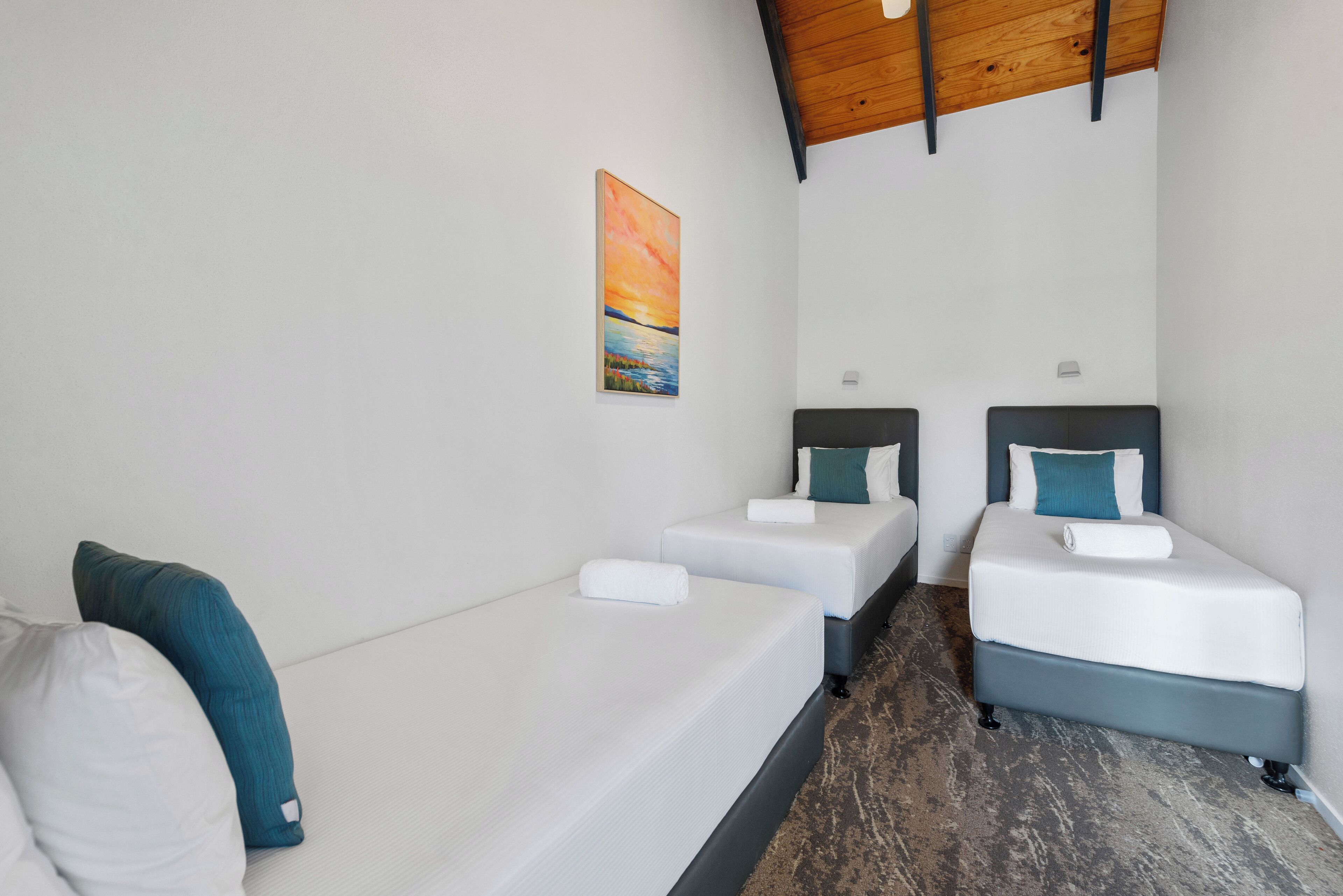 Habitació d'hotel amb dos llits individuals, un sofà i un quadre a la paret.