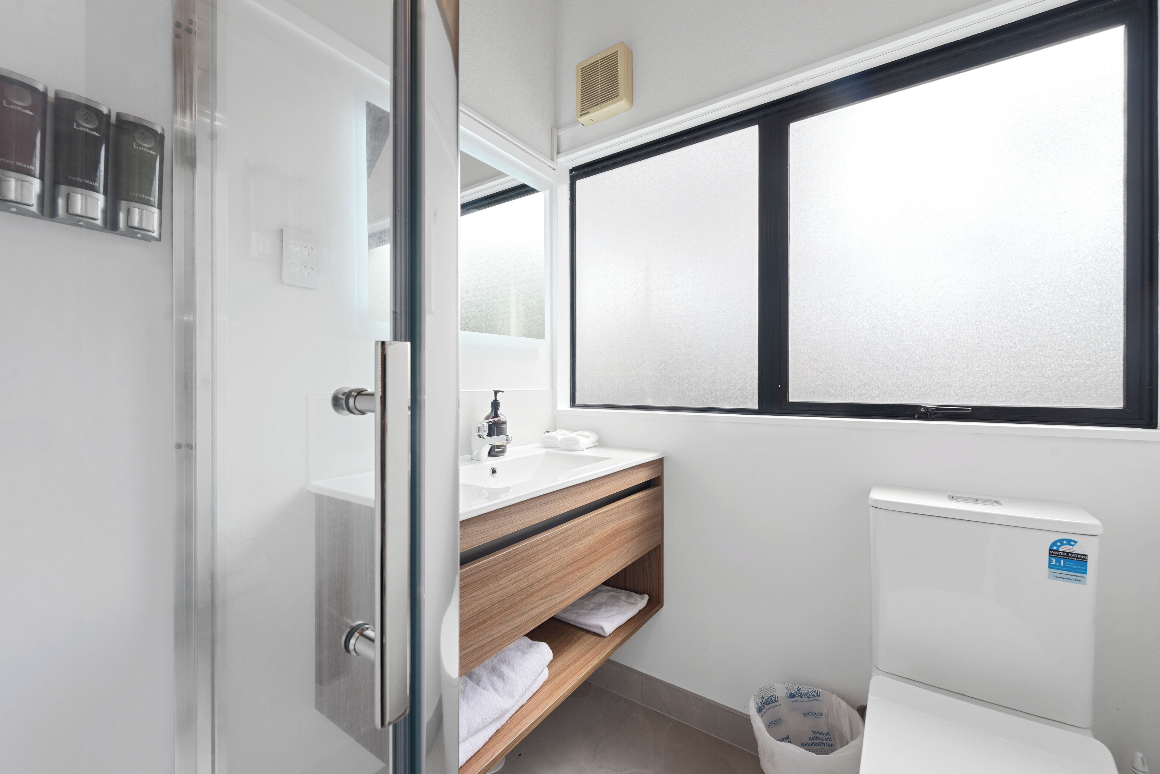 A bathroom with a white sink, wooden vanity, and a white toilet.
