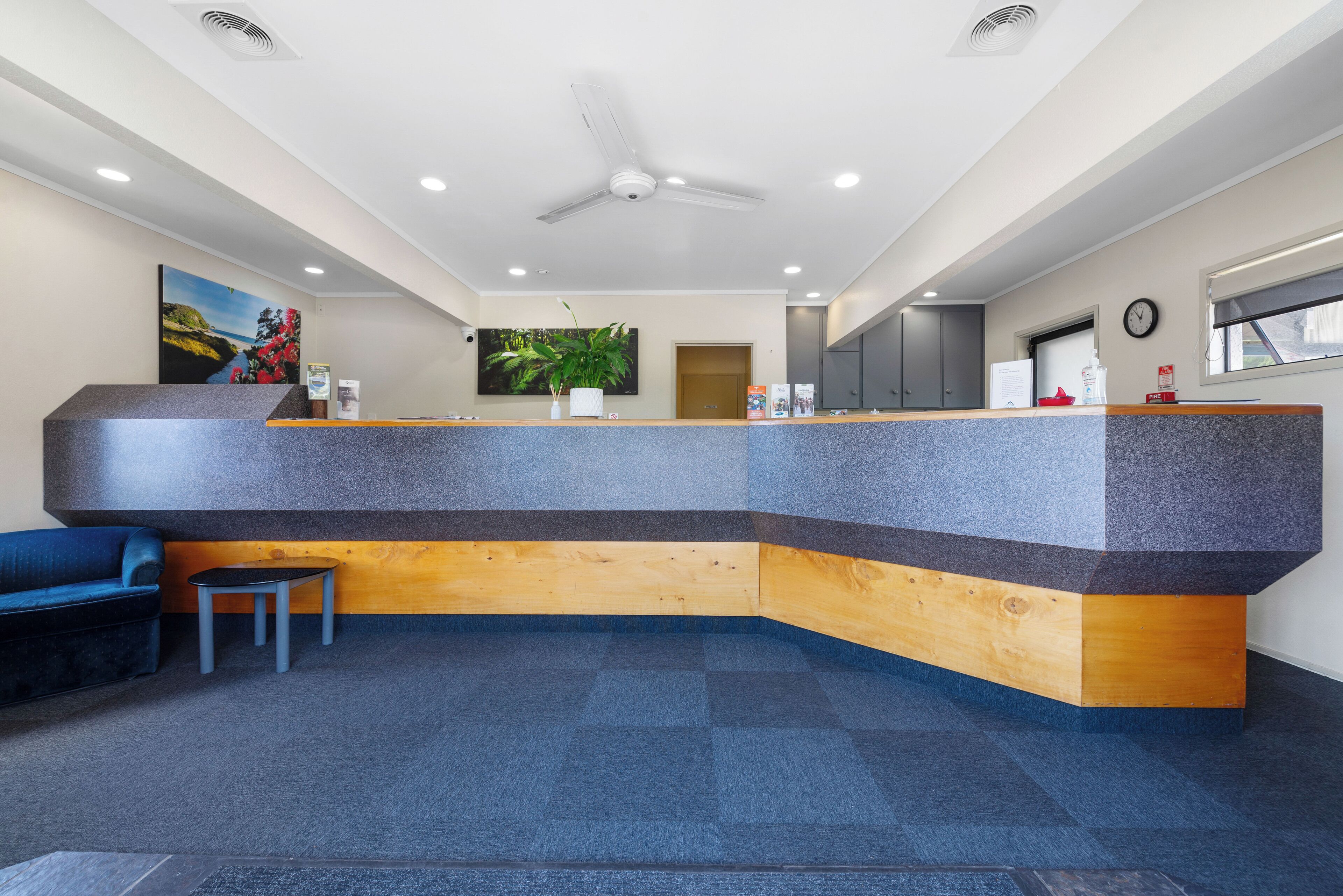A reception area with a curved counter, a ceiling fan, a clock, and a large window.