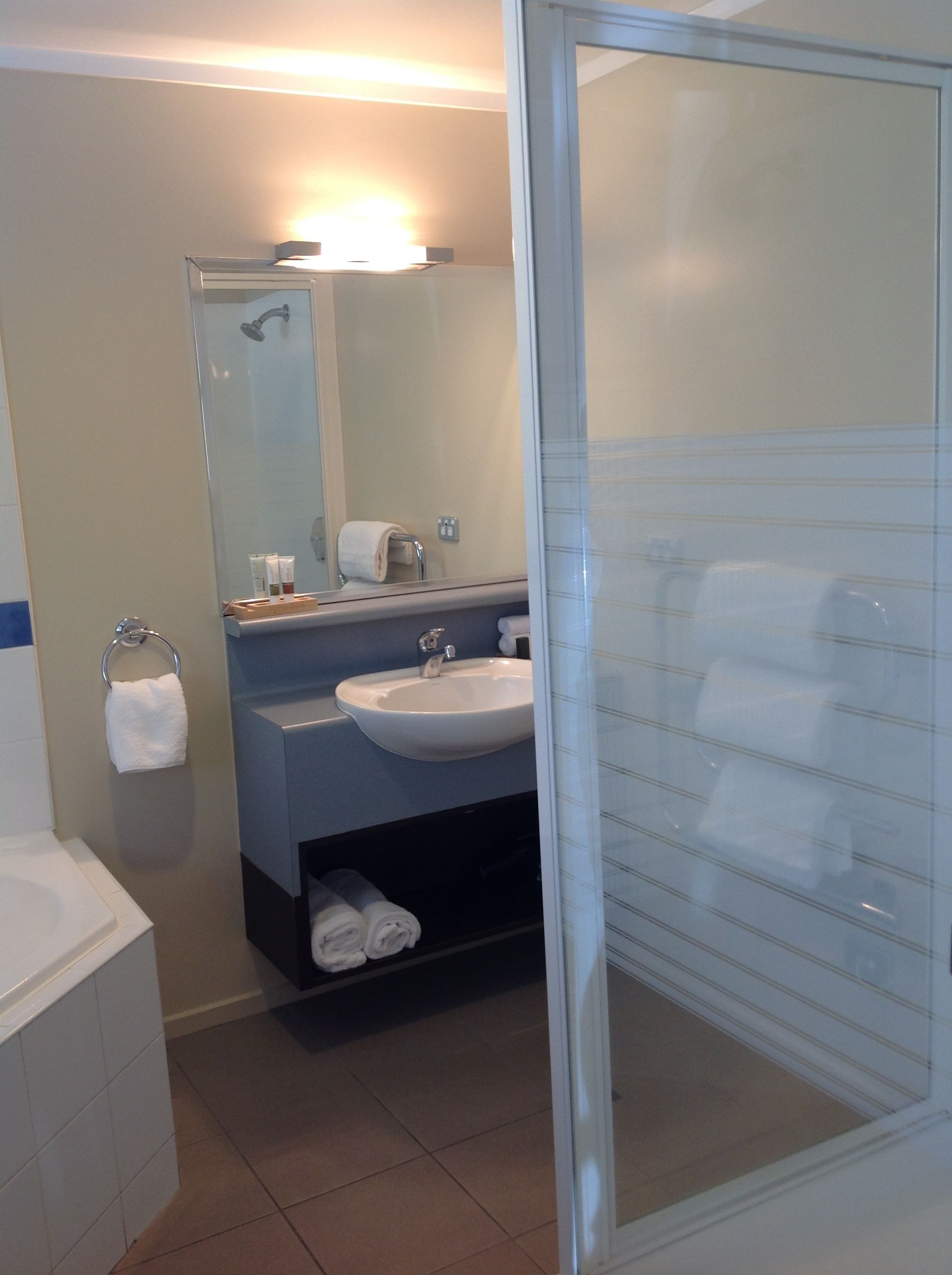 A modern bathroom with a glass shower enclosure, a sink, and a mirror.