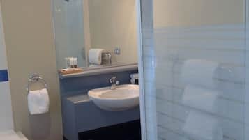 A modern bathroom with a glass shower enclosure, a sink, and a mirror.
