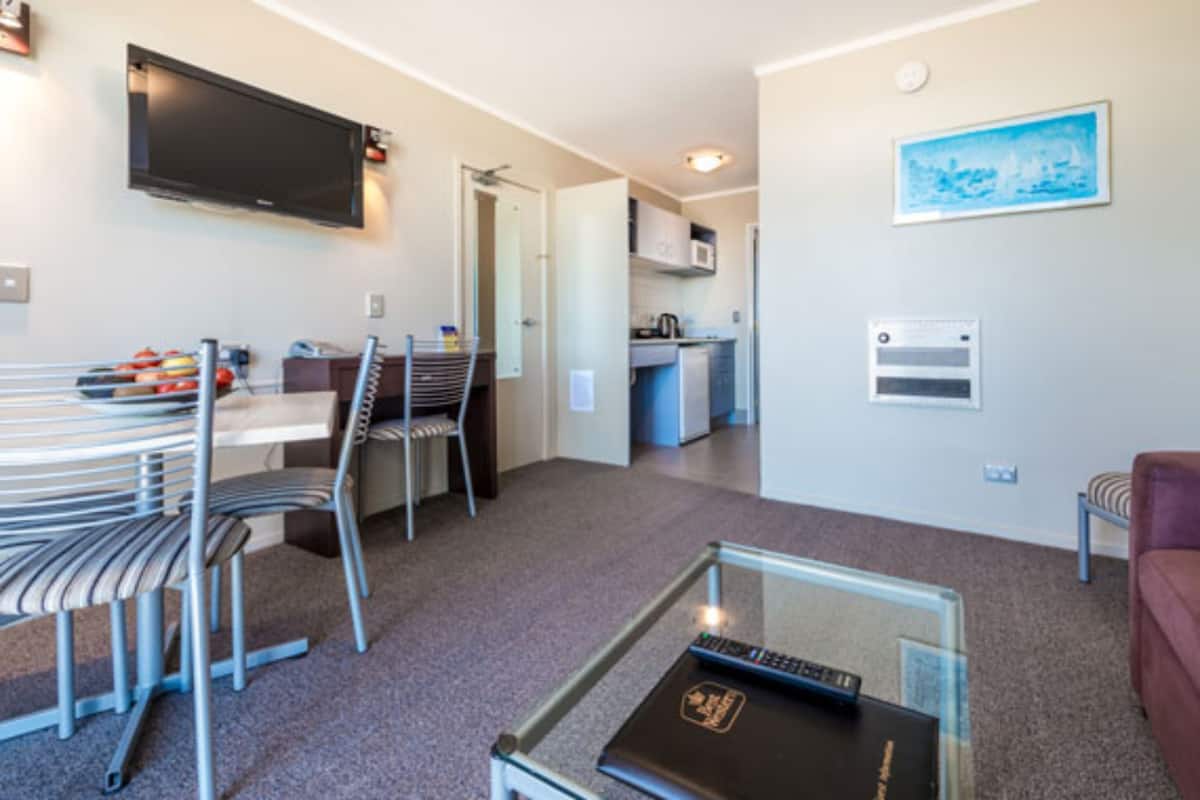 Un espace de vie compact comprenant un coin repas, une kitchenette et un téléviseur fixé au mur.