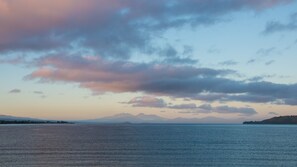A calm body of water with distant mountains and a clear sky. - Sails On The Lake (Taupo)