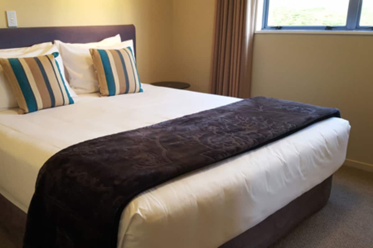 Une chambre d’hôtel avec un grand lit, une table de chevet et une fenêtre.
