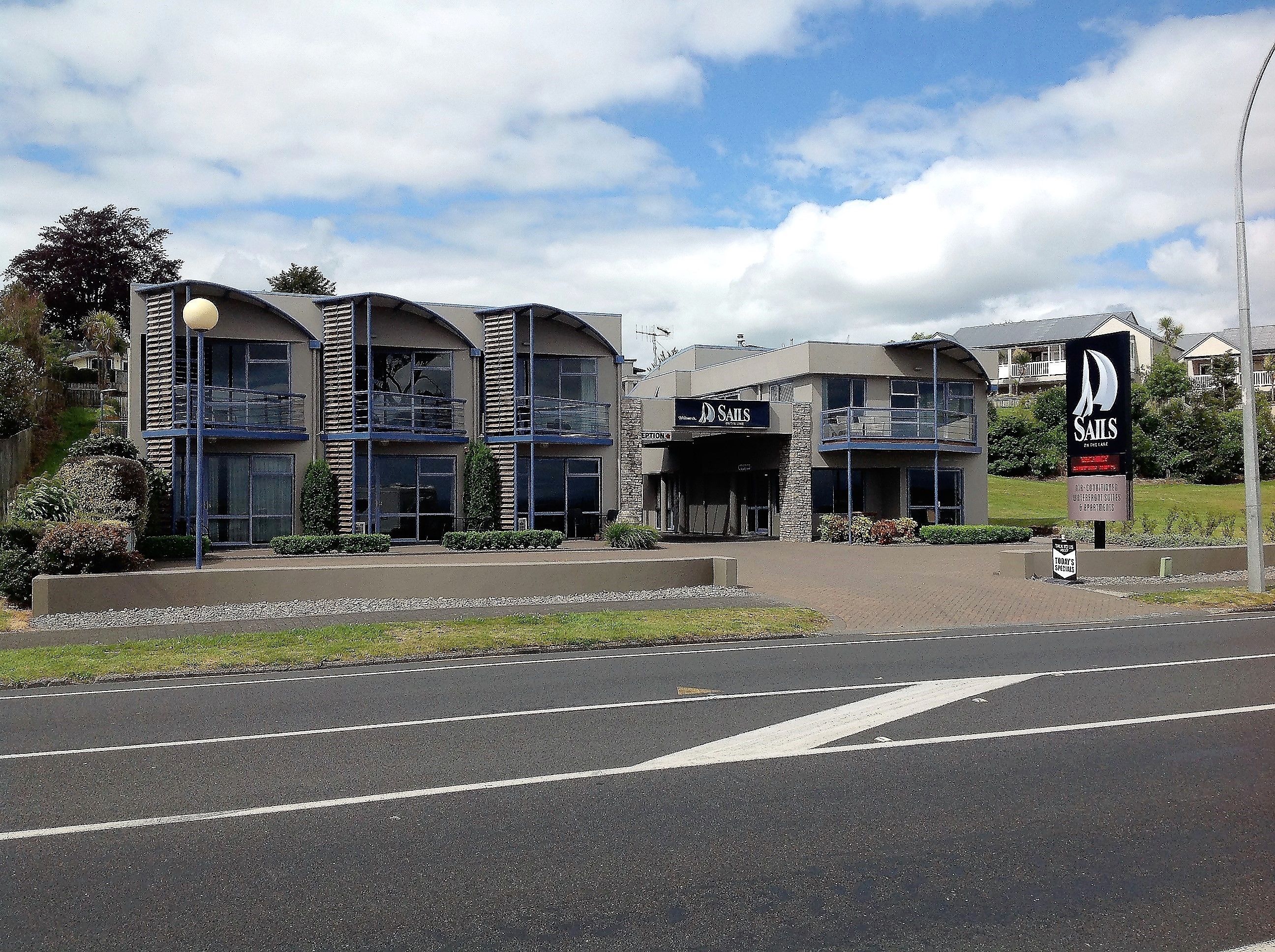 A modern building with a sign for 'Sails' indicating a marina or boating facility.