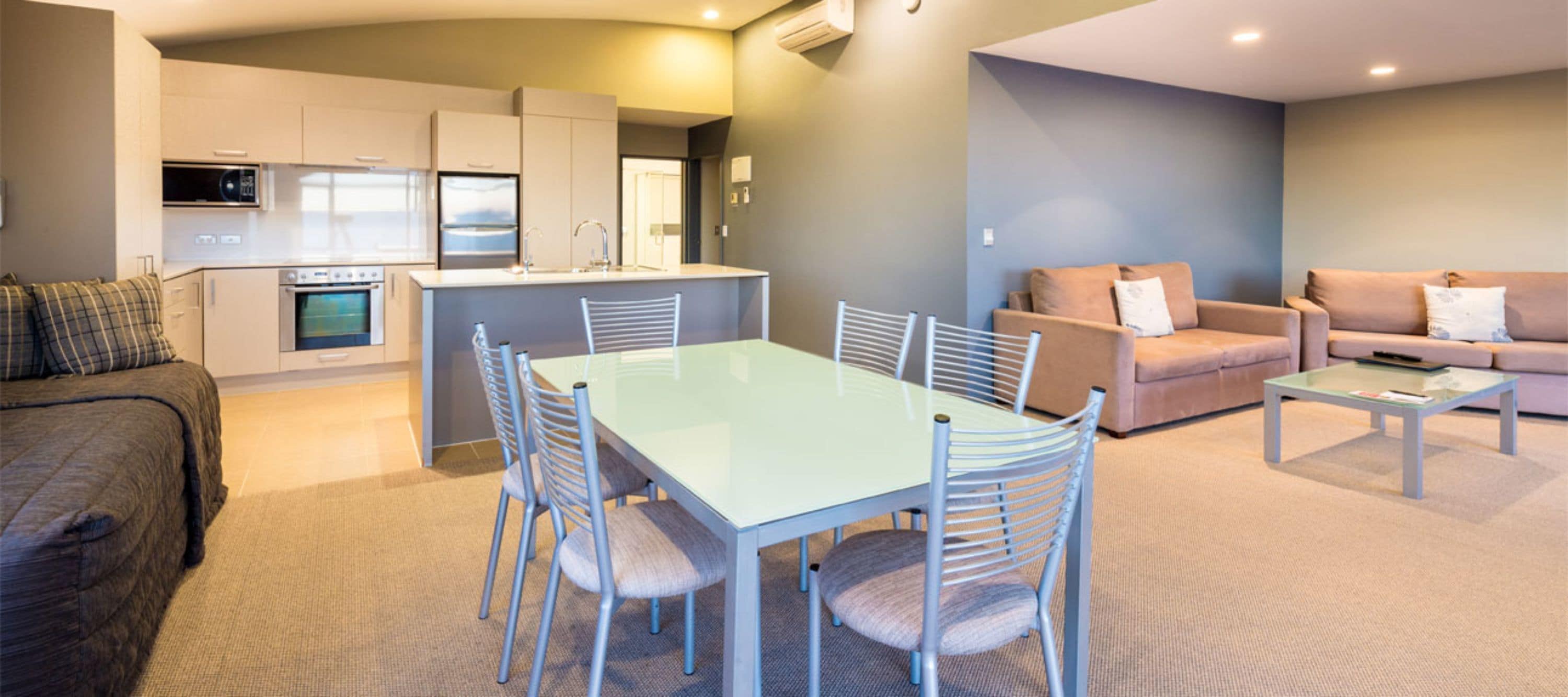 A modern living room with a dining area, a kitchen, and a sofa set.