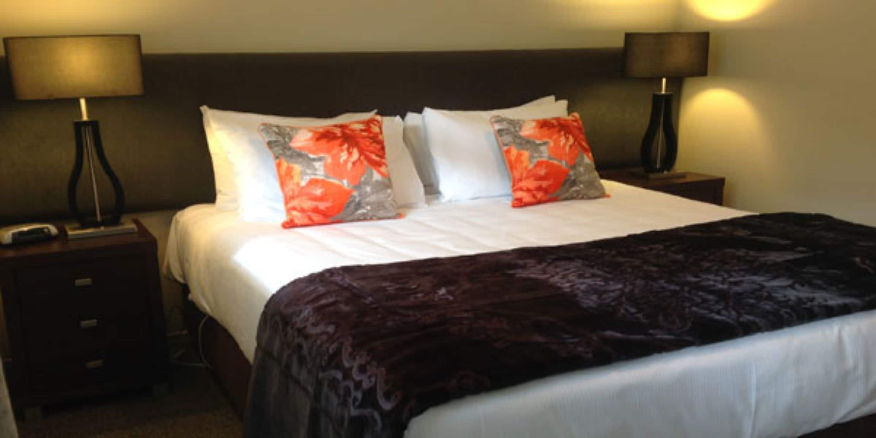 A hotel room with a large bed, two nightstands, and two lamps.