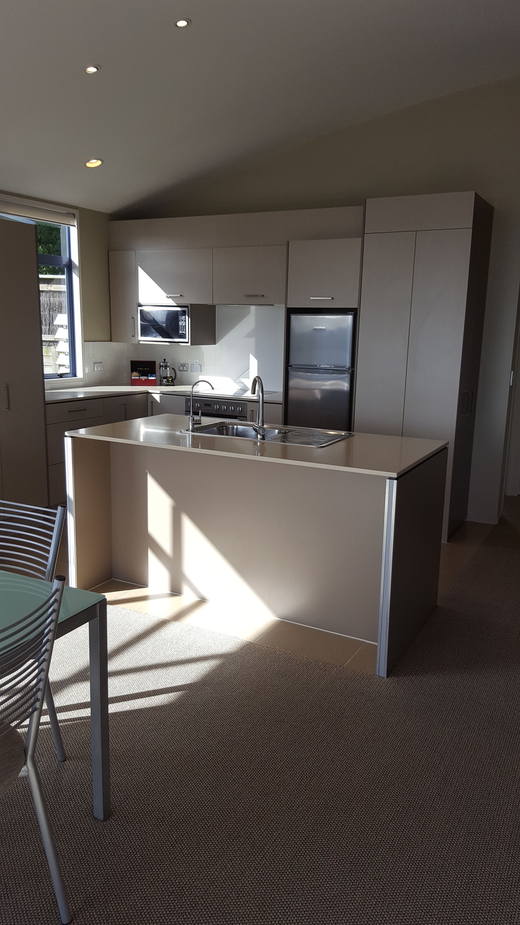 A modern kitchen with a central island, stainless steel appliances, and a large window providing natural light.
