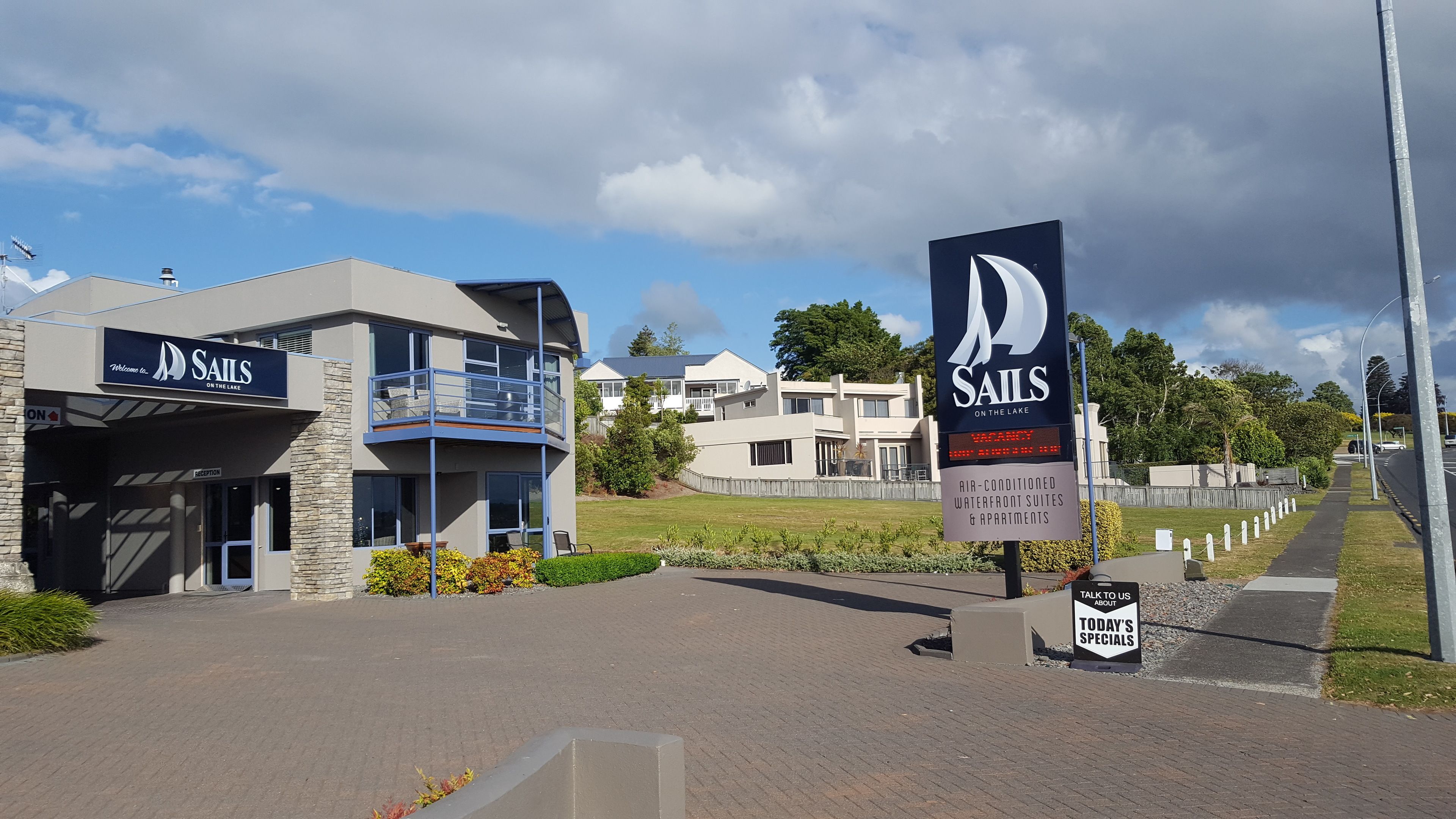 A modern building with a sign for 'Sails on the Lake' indicating waterfront suites and apartments.