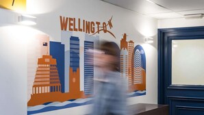 A wall with a cityscape mural labeled 'WELLINGEON' and a dark blue door.