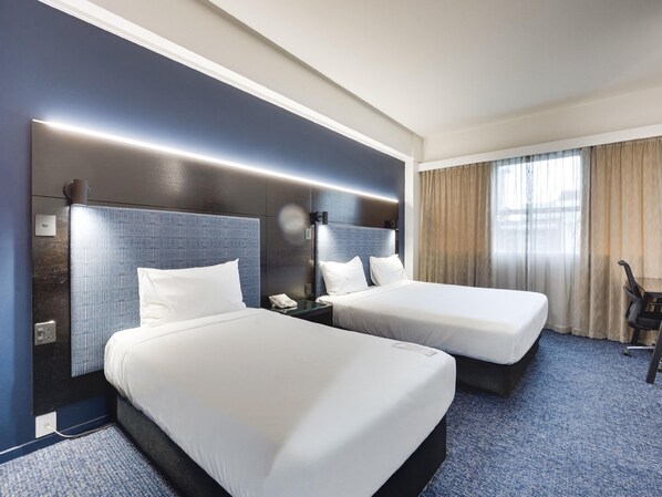 A hotel room with two beds, a desk, a chair, and a large window with curtains. - Mercure Wellington Abel Tasman (Wellington)