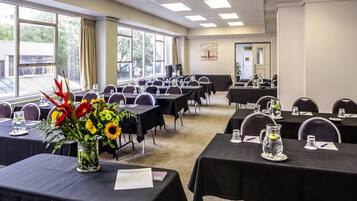 A conference room with tables, chairs, and a large window with curtains.