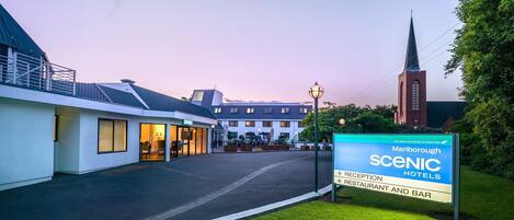 A hotel entrance with a sign for Marlborough Scenic Hotels, featuring a reception and restaurant area.